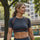 Woman in athletic wear standing outdoors with trees and buildings in the background