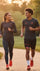 Two people running outdoors on a path with greenery in the background